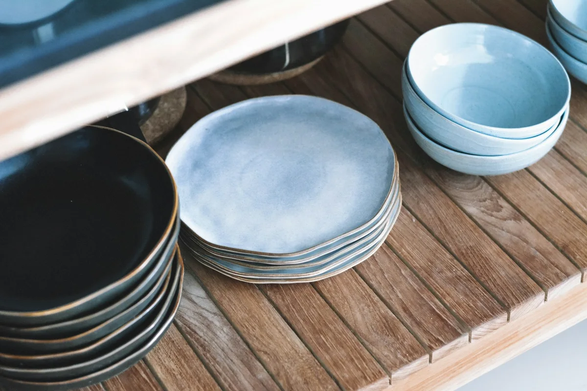 A collection of blue ceramic bowls and plates on timber shelving